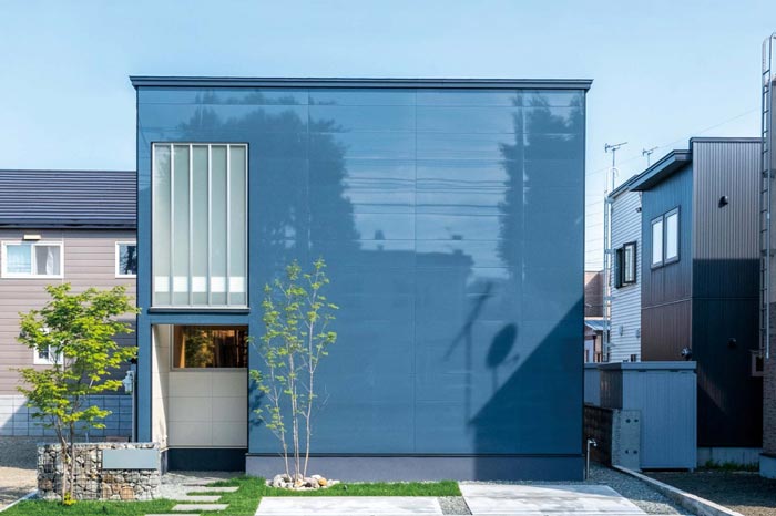 正面を鏡面仕上げのブルーグレーで統一した住宅