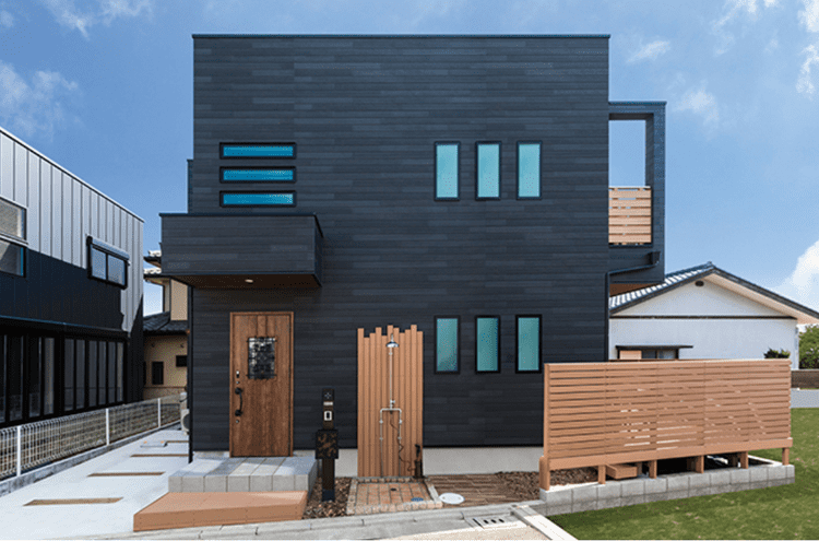 黒い外壁とウッド柄の開口部・外構の組み合わせの家