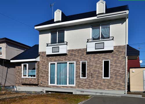 1階部分は模様、2階部分は白に塗られた住宅外壁