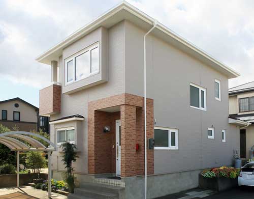 全体はクリーム色、玄関周囲のみレンガ調で仕上げた戸建住宅