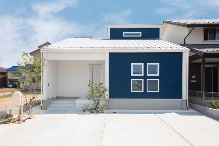 白と青を左右に塗り分けたツートンカラーの家