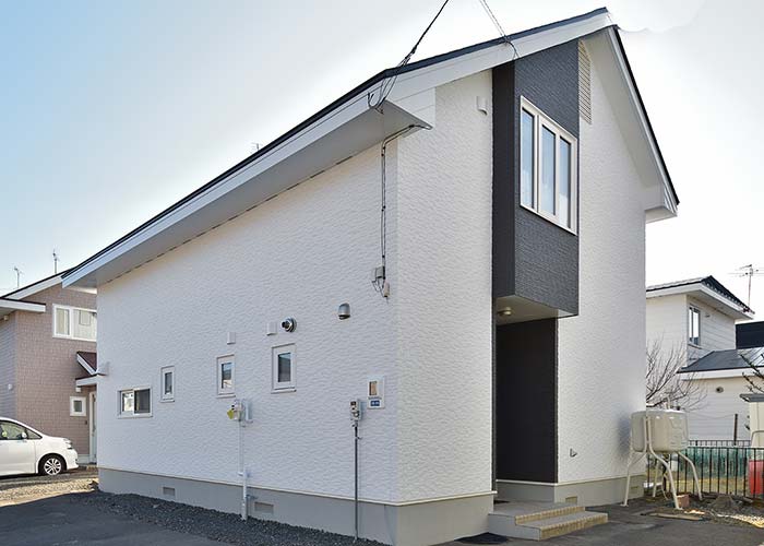 黒をポイントカラーにした白い外壁の家