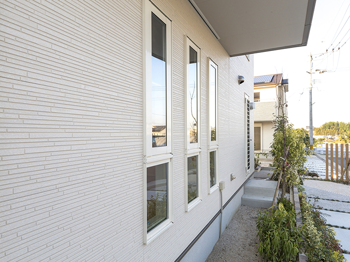 坂の斜面と平行な片流れ屋根とダークブラウンの外壁の住宅