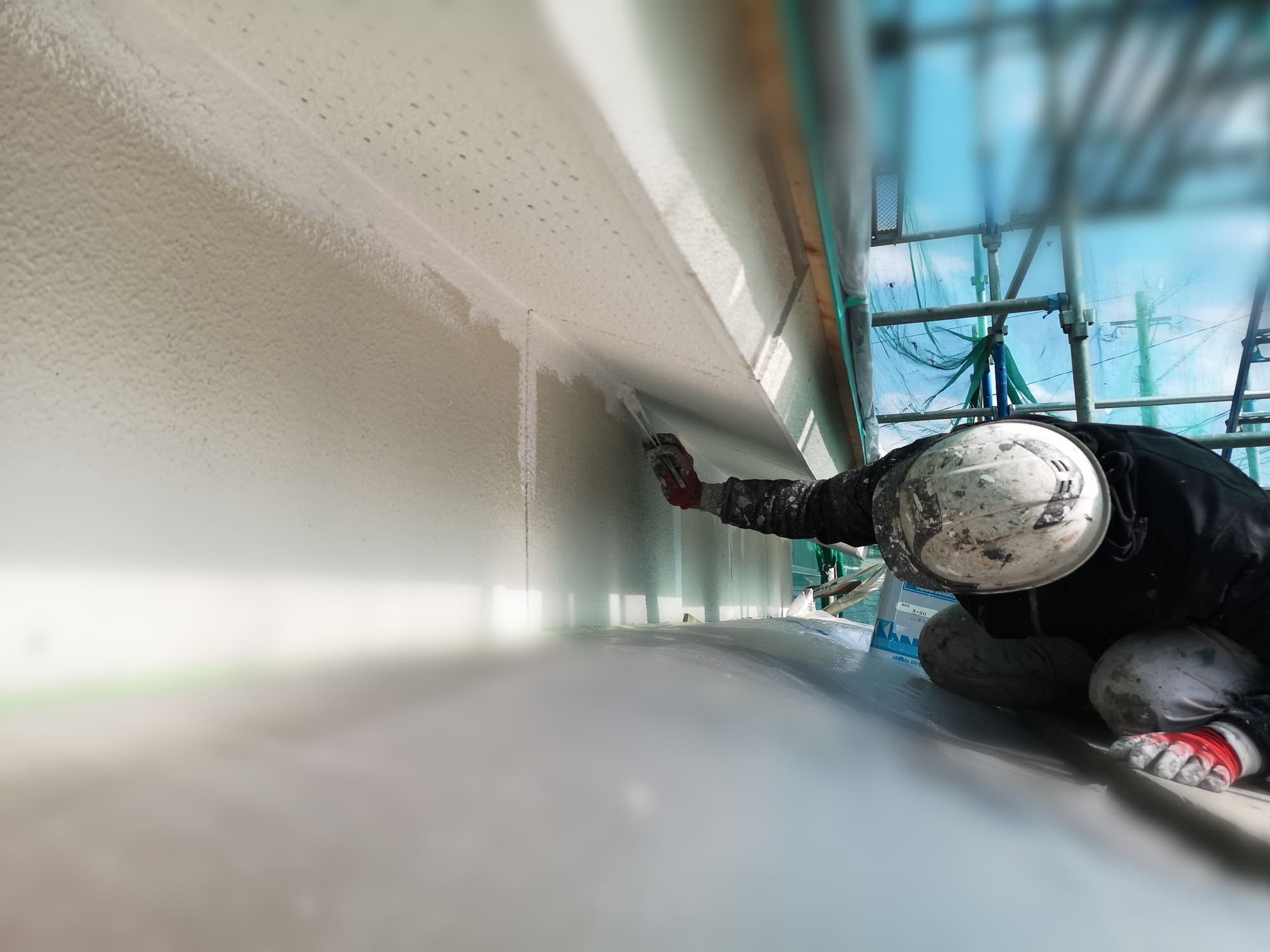 戸建て住宅の外壁上裏（軒天）をハケ塗り塗装する職人